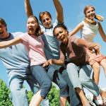 A stock image of a group of teens looking down and smiling at a camera.