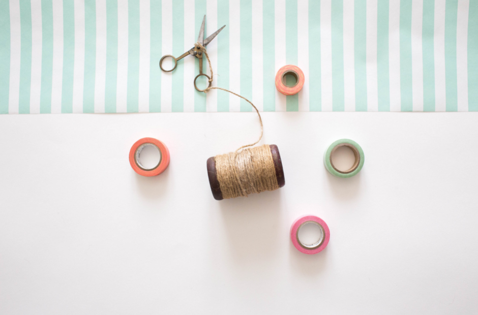 A pair of scissors and several spools of thread lying on a table