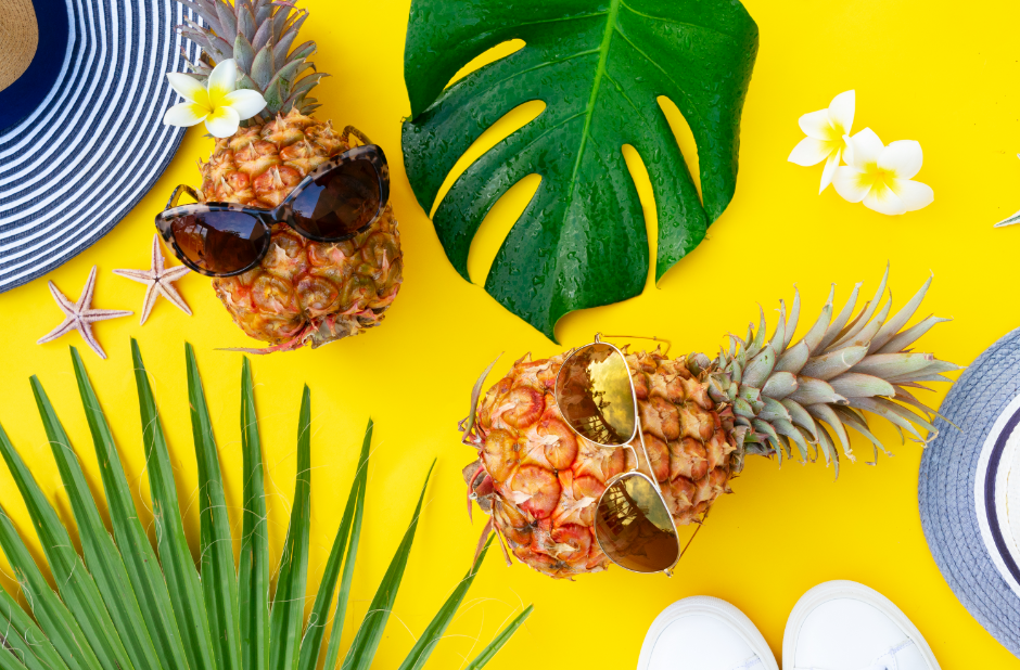 Pineapples lying on a yellow backdrop wearing sunglasses